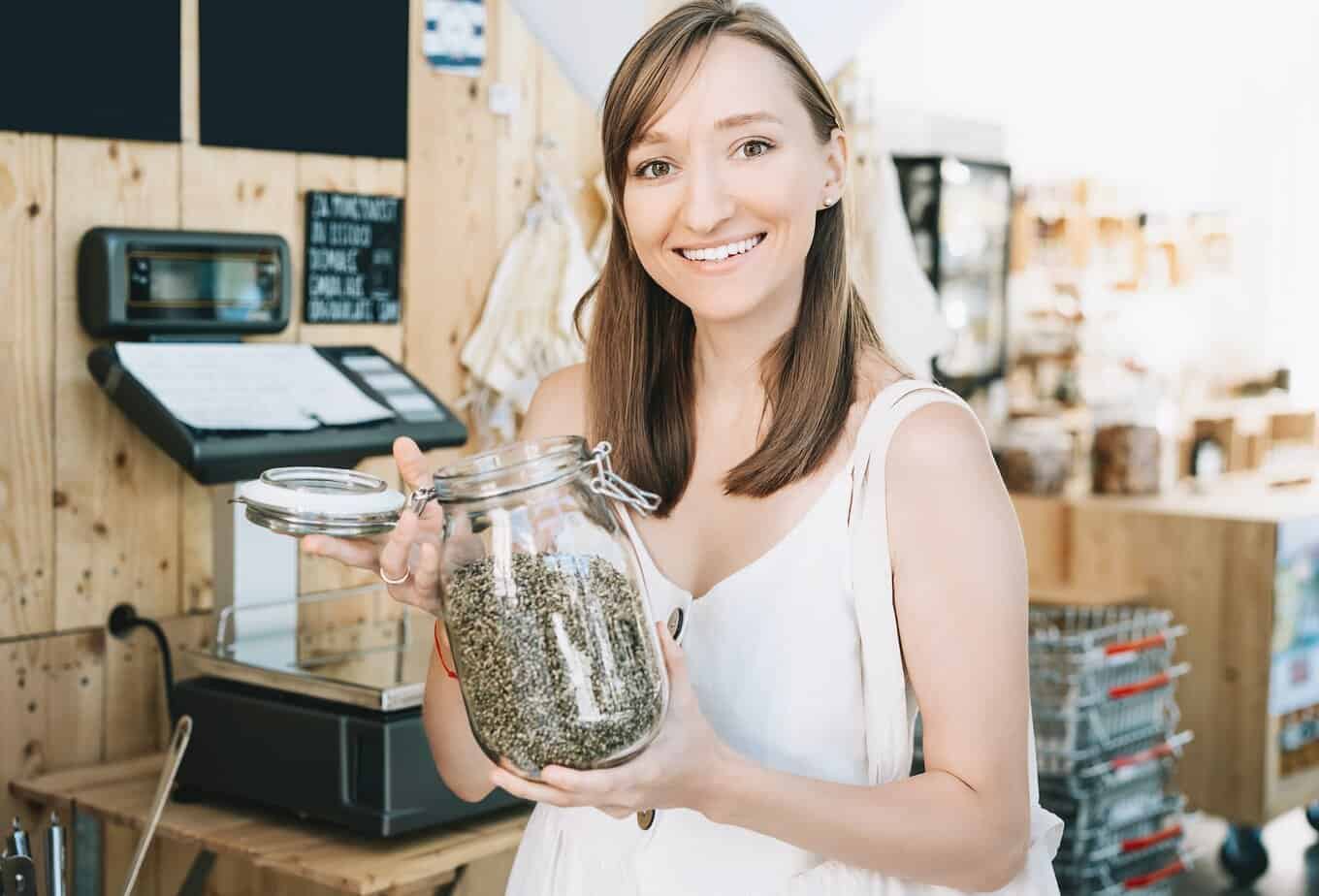 Girl holds glass jar with hemp seeds in zero waste shop cannabis business needs 10x traffic to increase roi
